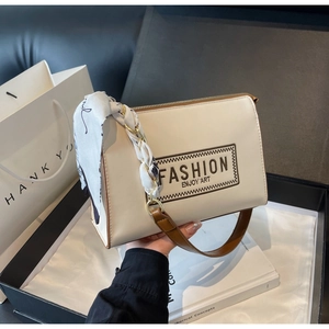 Detail of cream shoulder bag with brown strap, silk scarf and metal chain decoration