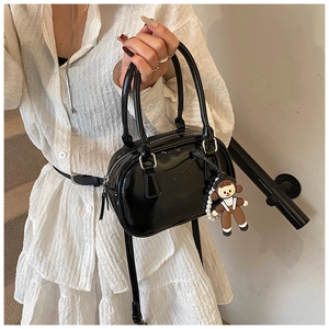 Detail shot of a black patent leather bowling bag with a cute girl doll charm
