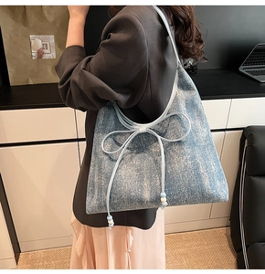 Dettaglio della borsa tote in denim azzurro con fiocco decorativo e perline di legno