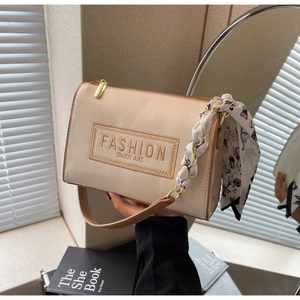 Detail of beige faux leather handbag featuring embroidery patch and floral silk scarf