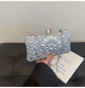 Detail of silver evening clutch bag with rhinestones, pearl closure, and chain strap