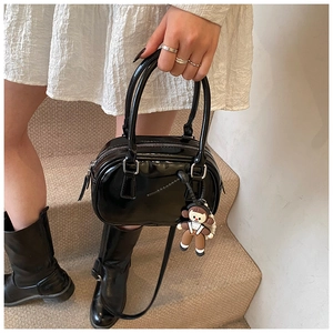 Polished black patent leather bowling bag with cute doll charm and detachable shoulder strap
