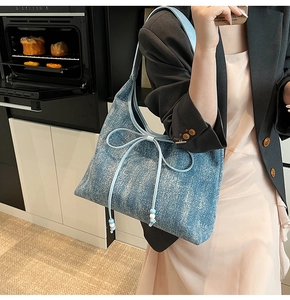 Dettaglio della borsa tote in denim con fiocco in pelle azzurra e perline decorative