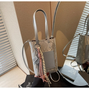Detail of silver marble tote bag with decorative tennis racket charm and leather pocket