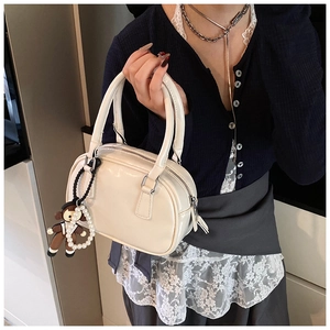 Detail of cream patent leather bowling bag with pearl chain and cute cartoon charm