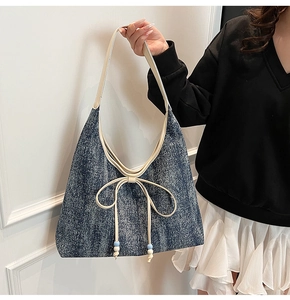 Dettaglio della borsa tote in denim con tracolla in pelle e fiocco decorativo con perline