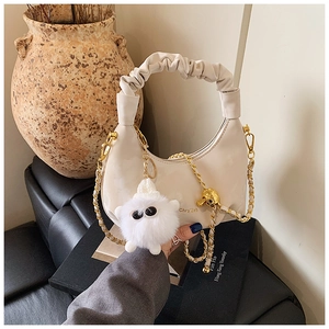 Detail of off-white pleated crescent bag with gold chain strap and plush monster charm