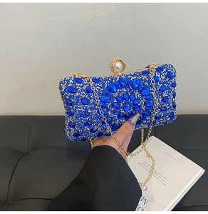 Close-up of deep blue crystal evening bag with a pearl clasp and gold chain detail