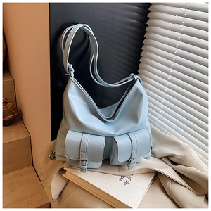 Detail of light blue PU leather tote bag with double front pockets and pin buckle straps