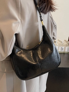 Minimalist black hobo dumpling bag in glossy pleated leather with gold hardware