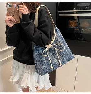 Dettaglio della borsa hobo in denim con fiocco in pelle crema e perline blu