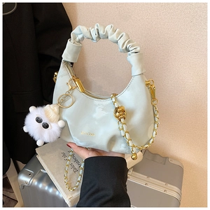 Detail of light blue pleated handbag with gold chain strap and cute plush sheep charm