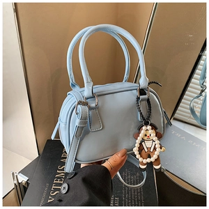 Light blue glossy bowling bag detail featuring a cute monkey charm and adjustable strap