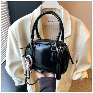 Detail of glossy black bowling bag featuring silver zippers and a cute doll charm