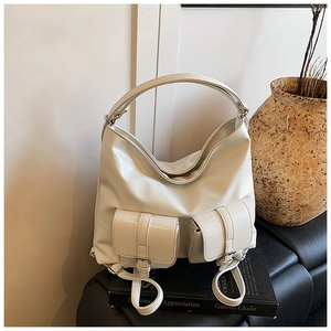 Minimalist beige PU leather tote bag with two buckle pockets on a leather bench
