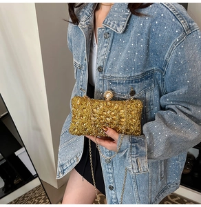 Close-up of luxury gold dinner clutch with crystals, pearl clasp and metal chain strap