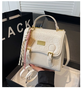 Détail du sac à main blanc en cuir PU gaufré avec boucles dorées et pompon