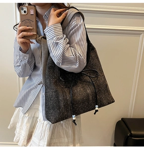 Dettaglio della borsa tote in tweed grigio con fiocco in pelle nera e ciondoli