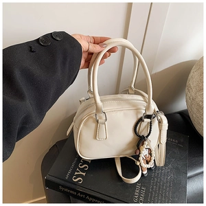 Detail of off-white bowling bag on art book with pearl charm and detachable strap
