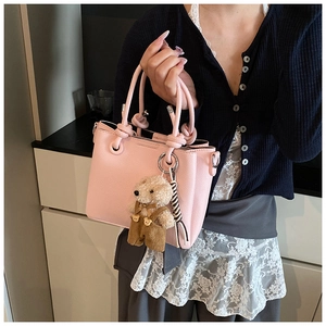 Detail van lichtroze bucketbag van leer met knoophengsel en schattige teddybeer-accessoire