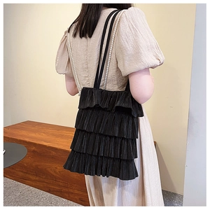 Détail du sac cabas noir à volants avec plis délicats et chaîne de perles élégante