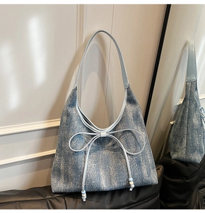 Dettaglio della borsa tote in denim azzurro con fiocco in pelle e trama argento
