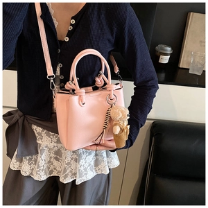 Detail van roze kunstlederen tas met geknoopte handgreep en schattige teddybeer