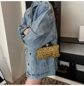Luxurious gold sequin evening bag with a large floral gemstone accent and metal chain