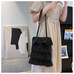 Détail du sac cabas plissé noir montrant la texture à volants et le tissu brillant chic