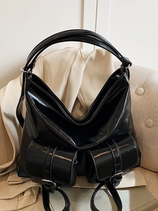 Fashionable black glossy faux leather tote bag with double pockets on beige sofa background