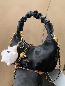 Pleated black hobo bag with golden chain, metal knot decor and white plush charm