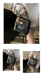 Détail d'un sac à main noir gaufré avec ferrures dorées et foulard en soie arc-en-ciel
