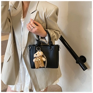 Detail van de zwarte lederen handtas met een schattige teddybeer-hanger accessoire