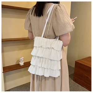 Vue détaillée du sac cabas blanc à volants avec bandoulière élégante en perles sur l'épaule