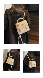 Détail du mini sac à dos blanc avec motifs gaufrés de cœurs et plaque métallique dorée