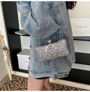 Silver rhinestone evening clutch with pearl clasp and chain strap on denim jacket