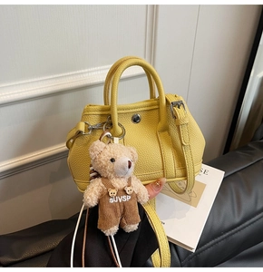 Detalle del mini bolso amarillo de piel granulada con colgante de osito de peluche