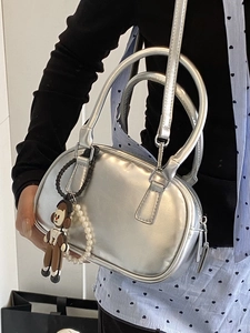 Silver metallic crossbody bowling bag with cartoon charm and pearl strap detail