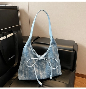 Dettaglio della borsa tote in denim blu con elegante fiocco in pelle e tracolle lunghe