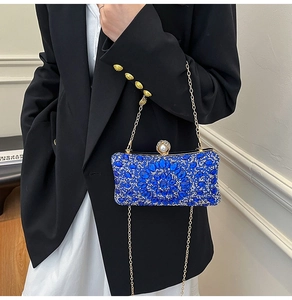 Close-up of royal blue crystal evening bag with pearl clasp and gold chain detail