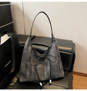 Dettaglio della borsa tote in denim glitterato con fiocco in pelle e nappine di perle