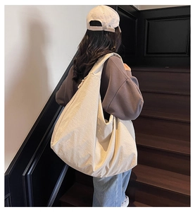 Detailed view of the beige oversized crescent tote bag showing its soft nylon texture