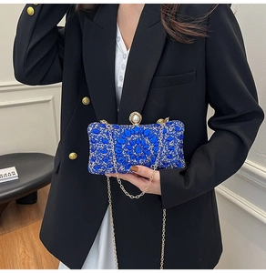 Close-up of luxury navy blue evening clutch with crystal floral patterns and pearl clasp