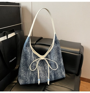 Dettaglio del tessuto denim della borsa hobo con fiocco in pelle bianca e perle