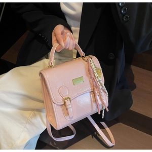 Détail du sac à main rose clair en similicuir gaufré avec boucle dorée et foulard en soie