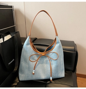 Dettaglio borsa tote in denim con fiocco in pelle marrone e nappe di perline