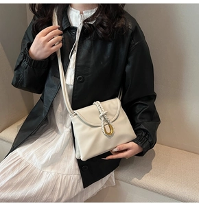 Close-up of cream envelope bag with woven rope detail and golden U-shaped hardware buckle