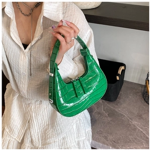 Detailed close-up of emerald green crescent bag with glossy crocodile texture pattern