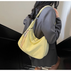 Detail of soft yellow hobo bag with braided rope charm shown in lifestyle shot