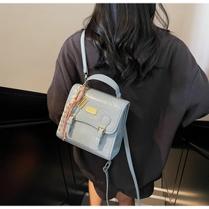 Vue détaillée du sac à dos gris-bleu clair texturé porté sur le dos du mannequin